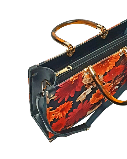 an image showing zipline of a floral tote bag with red and orange flowers on a black background, featuring a tortoise top handle.